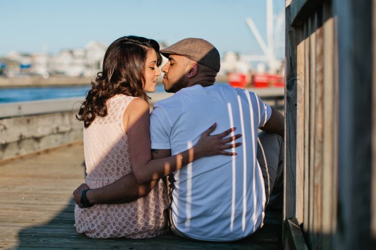 Couple kisses on the boardwalk at Point Pleasant inlet during their engagement photo session with their monmouth county nj wedding photographers markow photography