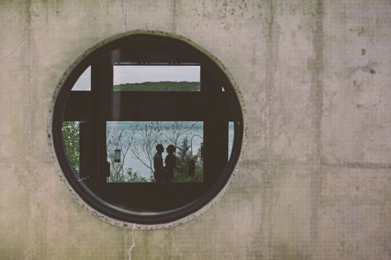 couple embraces through window at the manasquan reservoir during their engagement photo session with their monmouth county nj wedding photographers julianne and steven of markow photography